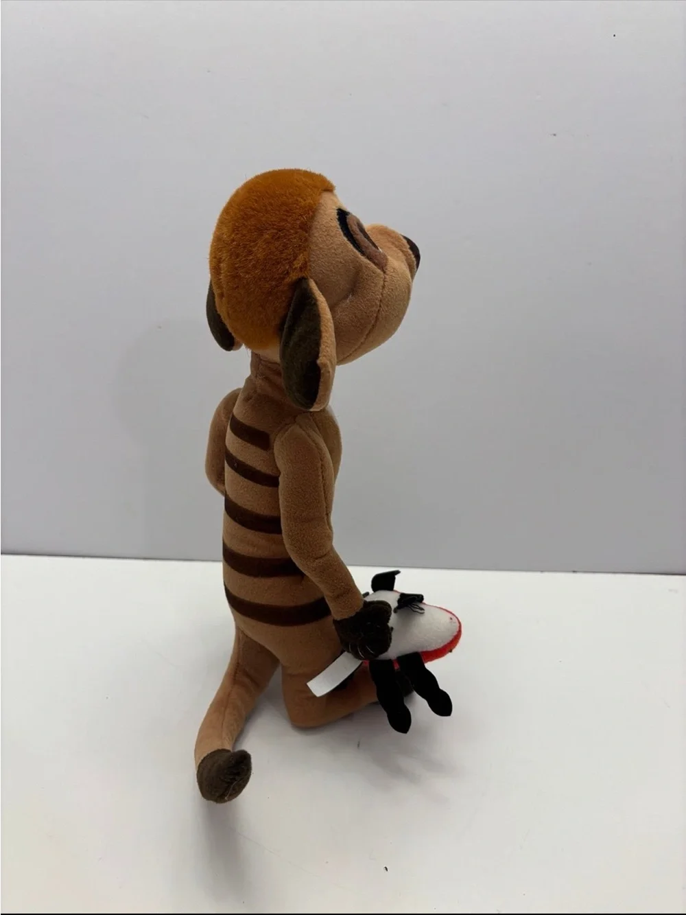 Disney The Lion King Timon plush toy holding a small red ladybug